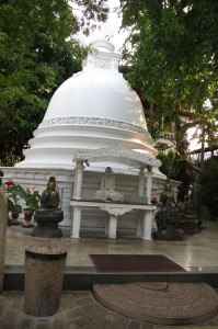Coral-white stupa and serene Buddha statues on tranquil temple grounds